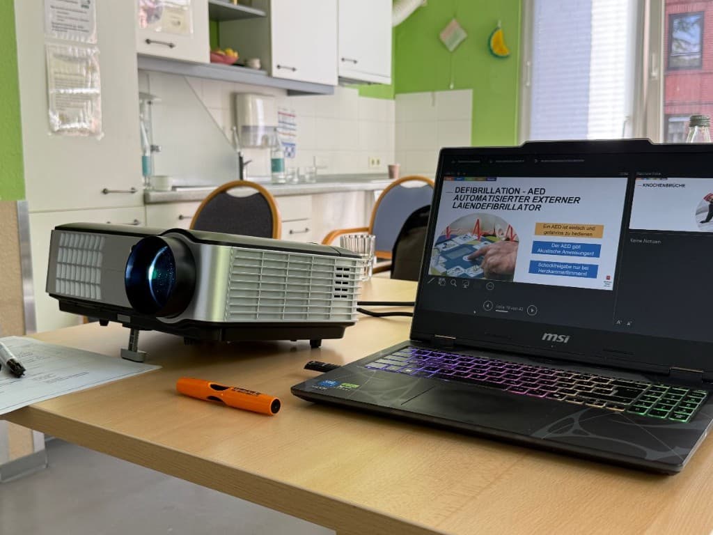 Laptop und Beamer mit Präsentation zum Thema Defibrillation und AED